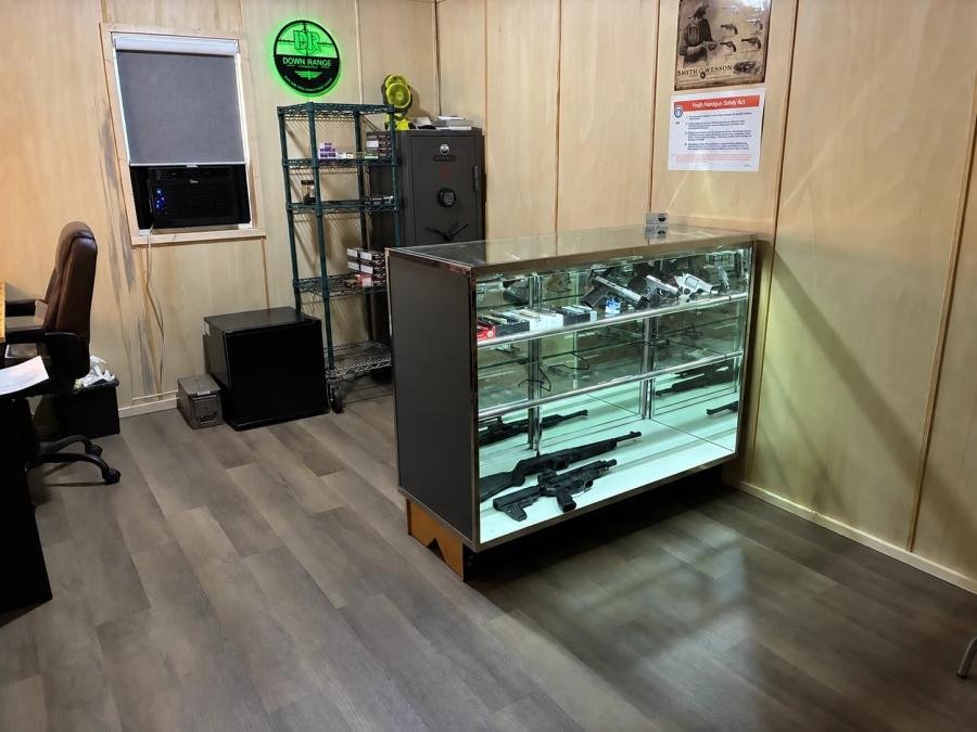 Down Range Firearms shop interior with glass display case and lit DR sign